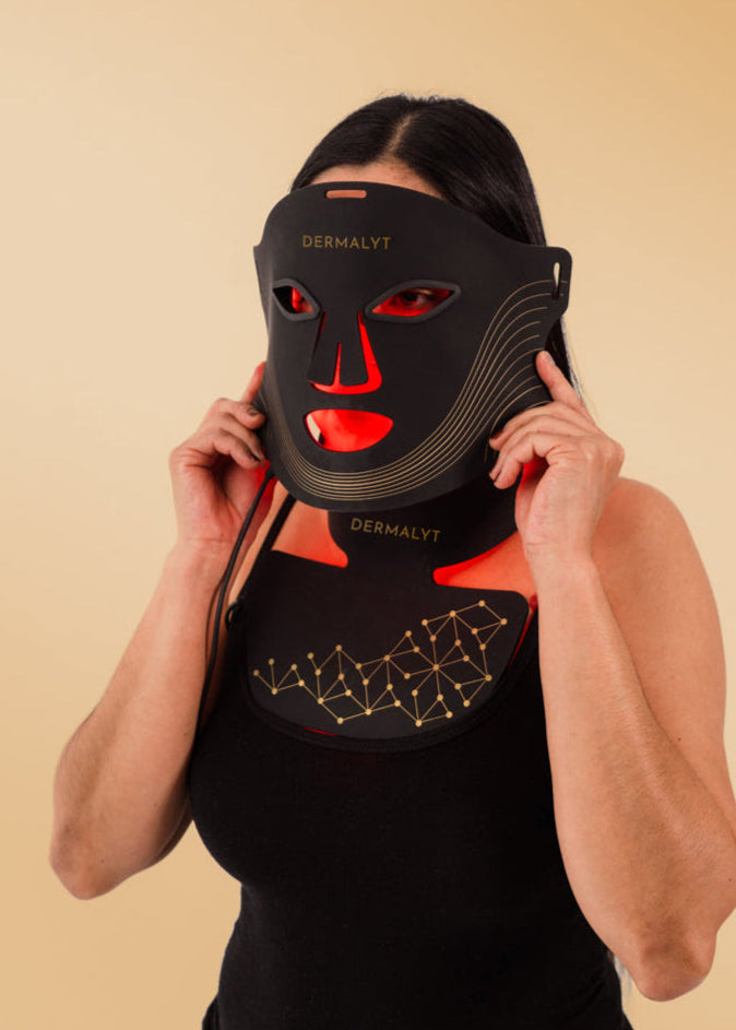 Person wearing a black face mask with red accents on a beige background